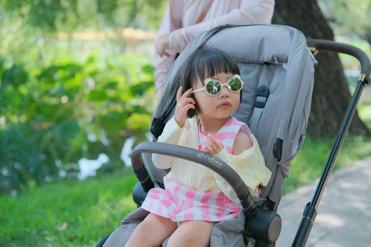 A little girl sitting in a stroller talking on a cell phone