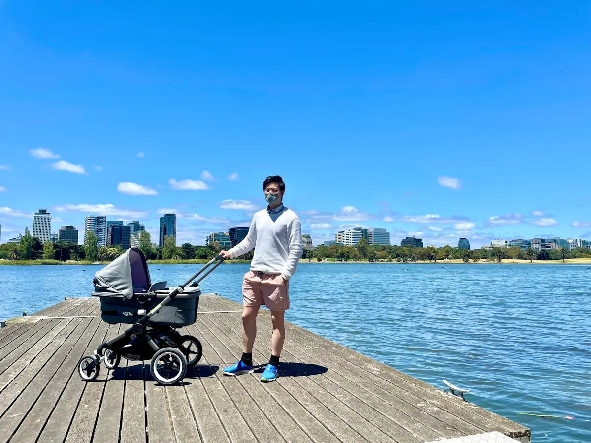 a man standing on a pier next to a baby carriage