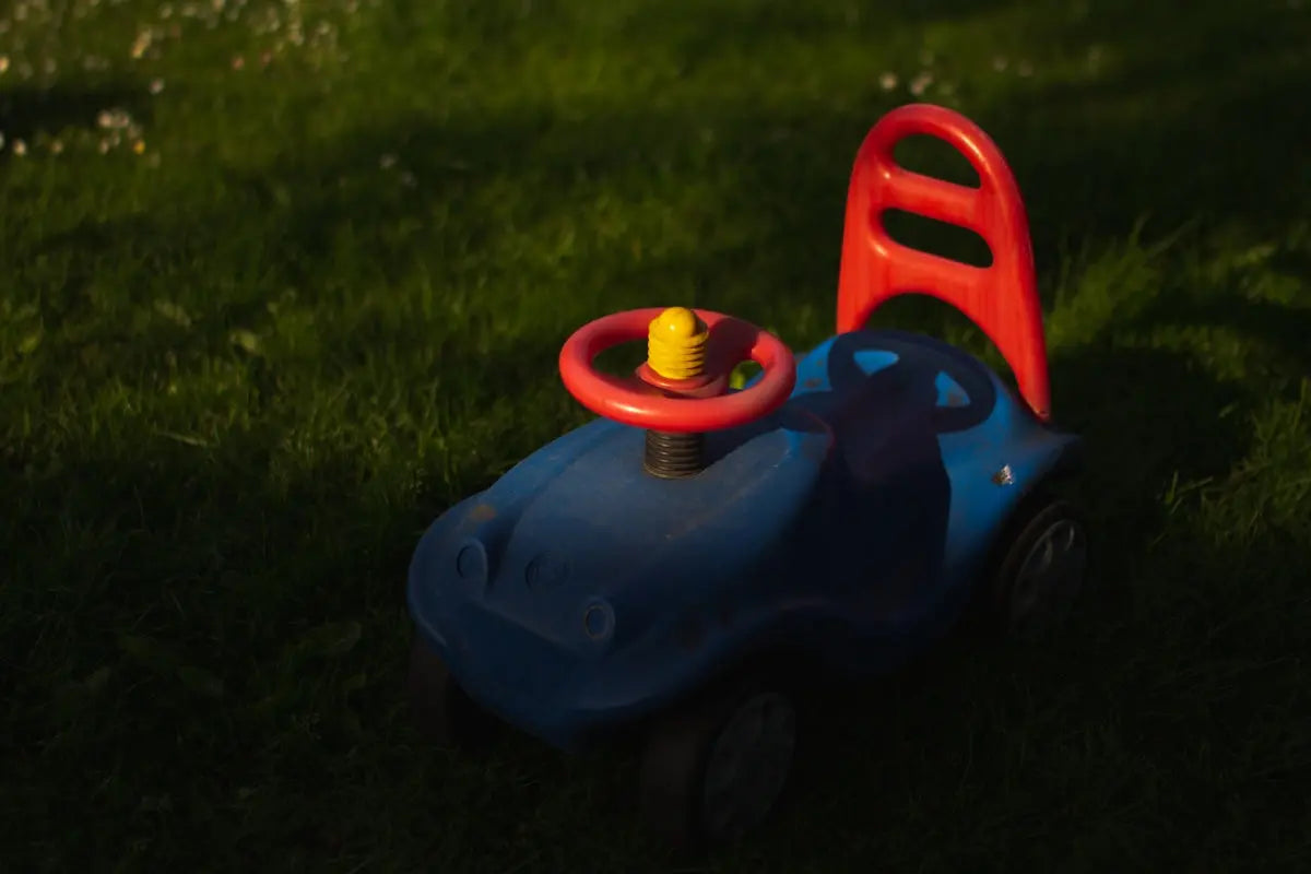 a toy car with a yellow top and a yellow top sitting in the grass