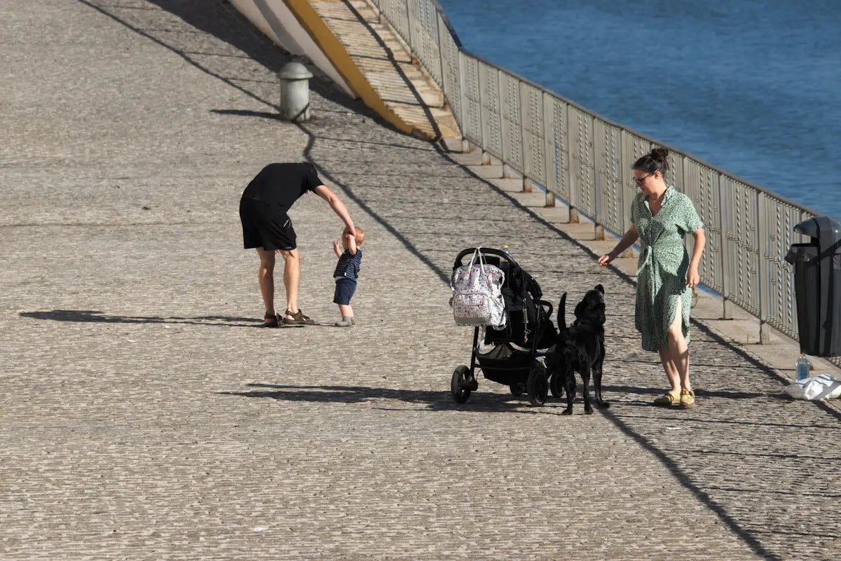 A man and a woman walking down a sidewalk with a baby in a stroller