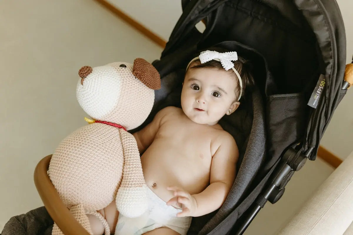 A baby sitting in a stroller with a stuffed animal